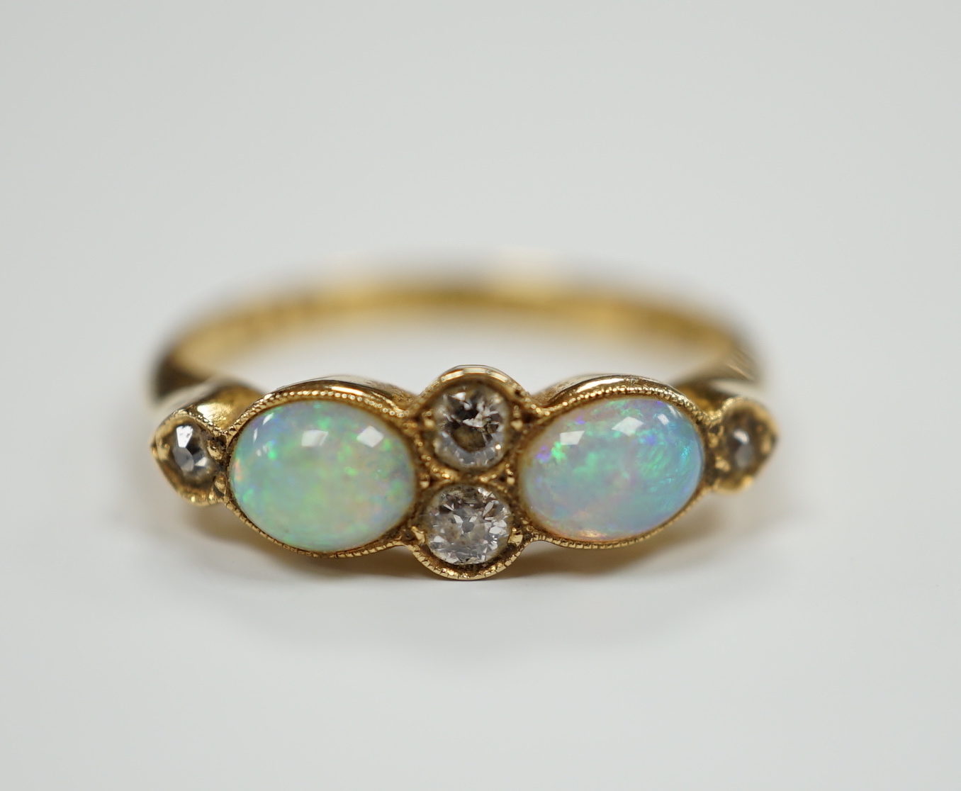 A George V 18ct gold, two stone white opal and four stone diamond chip set half hoop ring, Birmingham, 1917, size P, gross weight 3.6 grams.